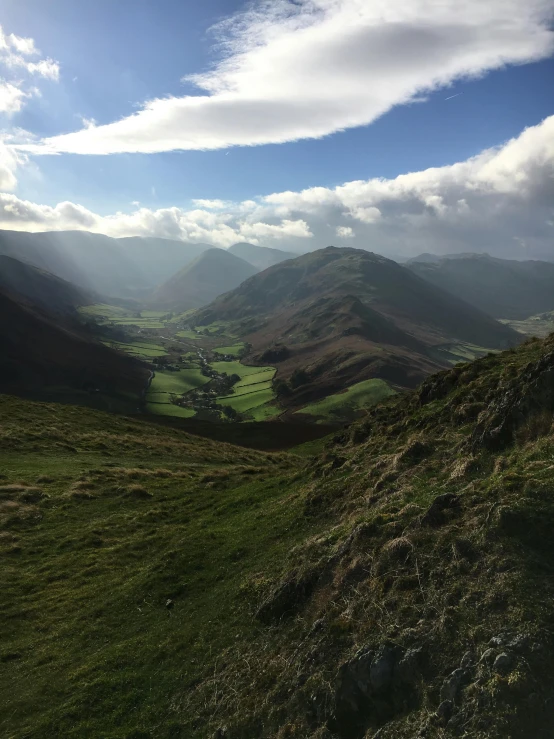 a view of a green valley and mountains, in the distance