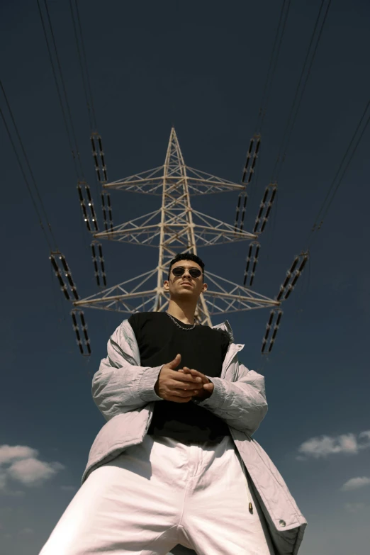 a man in sunglasses is leaning on a pole with electric lines behind him