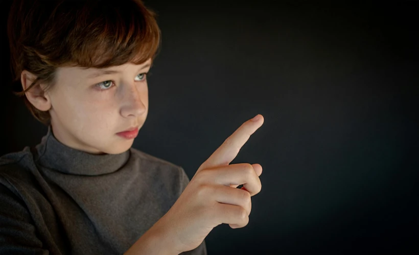 a young child pointing to soing with both hands