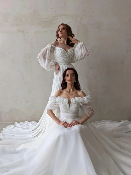 a woman in a white dress and another women wearing dress