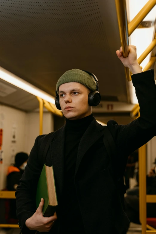 the man is wearing headphones and holding a book