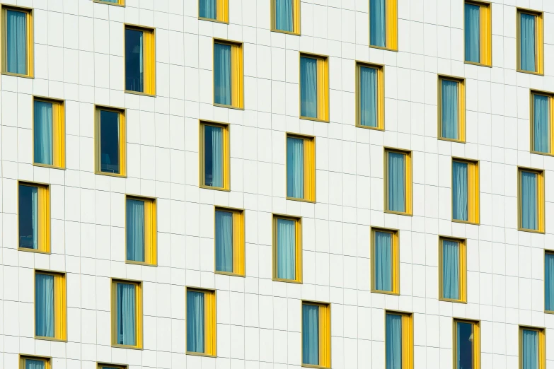 the bottom half of a tall building has many windows and yellow bars