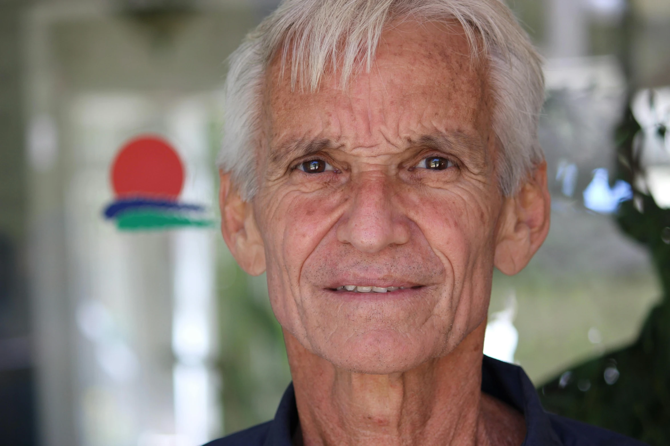 an older man with white hair looking at the camera