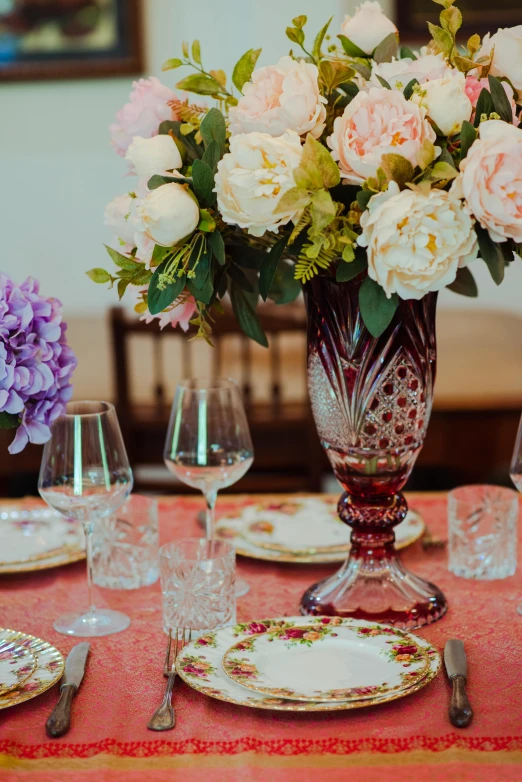 a dining table with plates, cups and vase