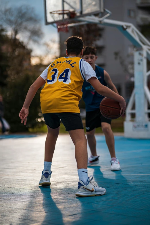 a boy on a basketball court playing in the sun