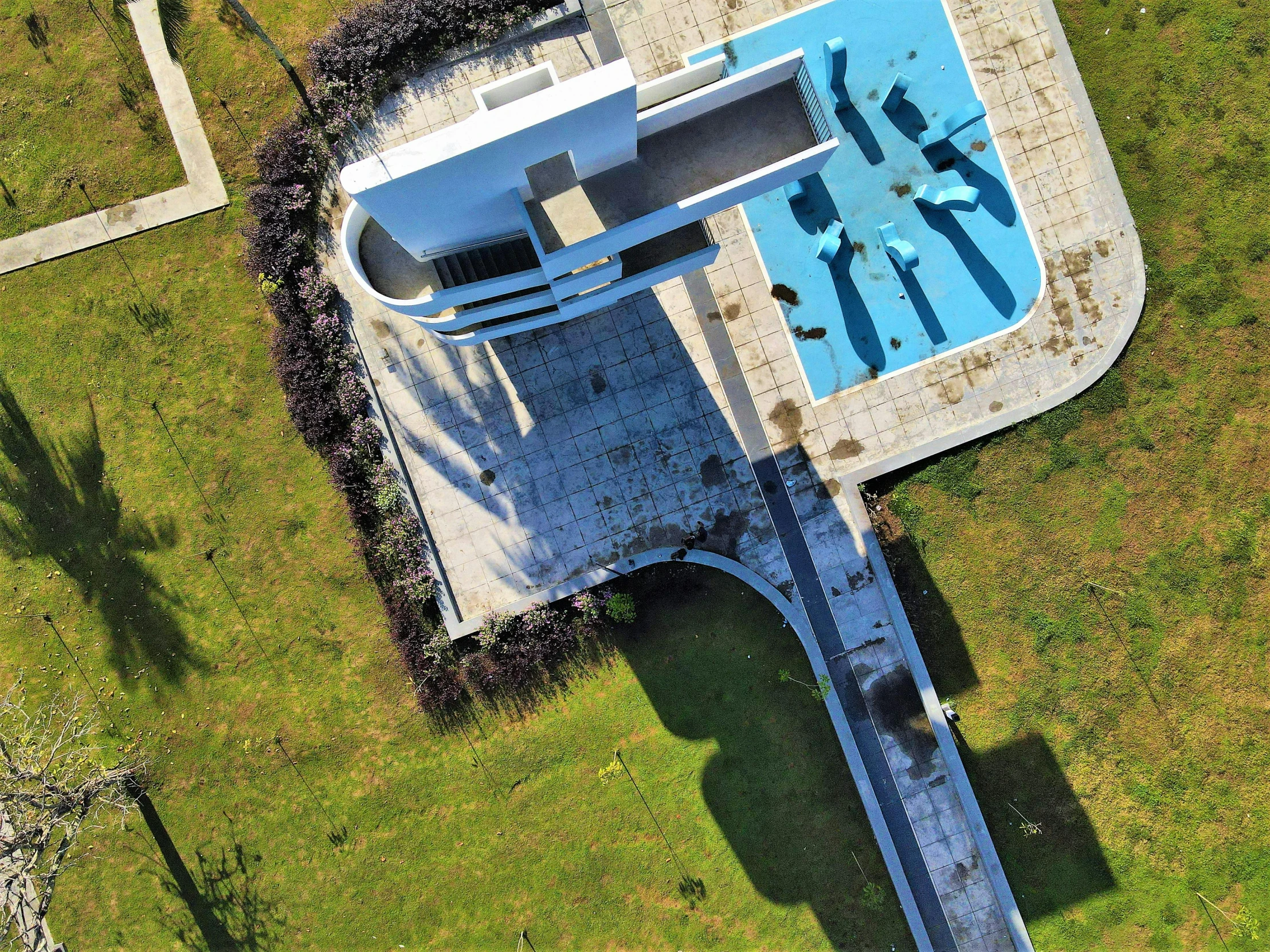 an aerial view of a swimming pool and green lawn area