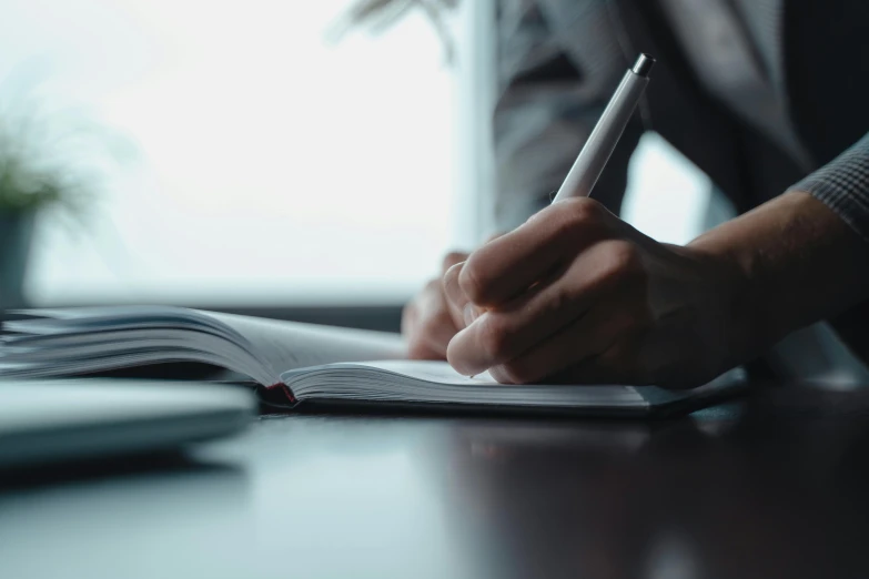 a person in a grey suit sitting down writing on a paper