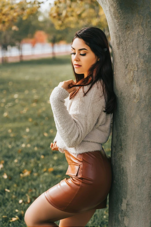 young woman leaning on a tree posing for the camera