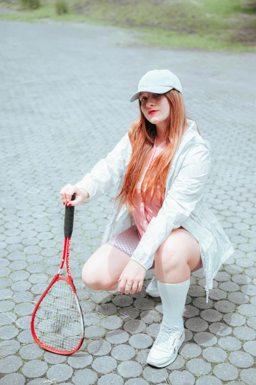 a woman squats with a tennis racket in her hands