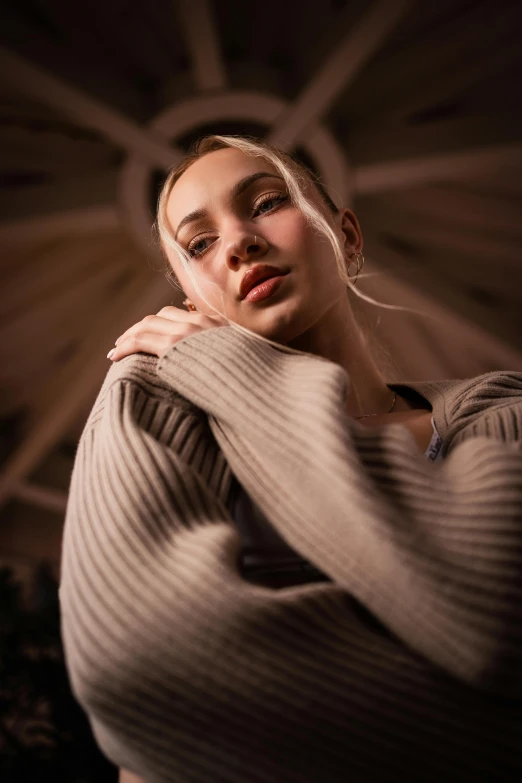 a girl wearing a brown sweater and eyeliner, poses for a po