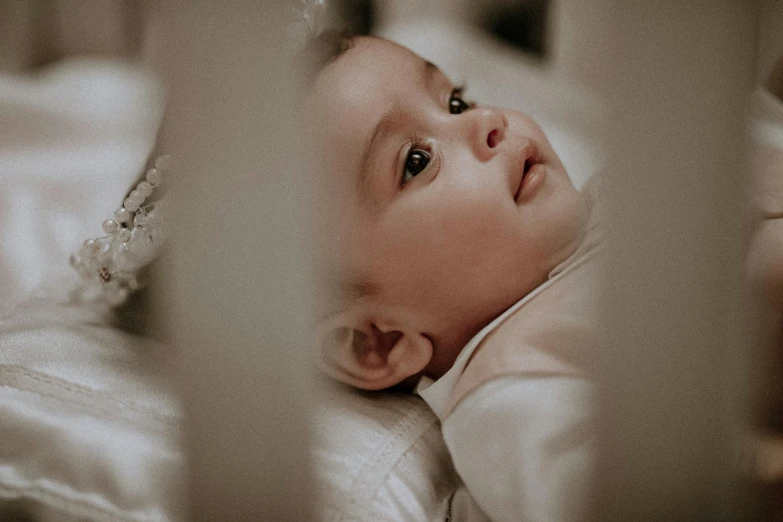 a baby lying on its back in a bed with white sheets