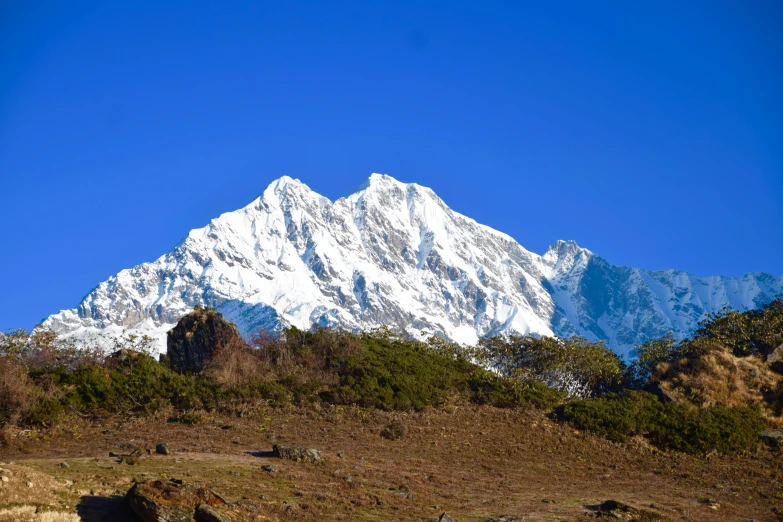 the snow - covered mountains rise high over some grass