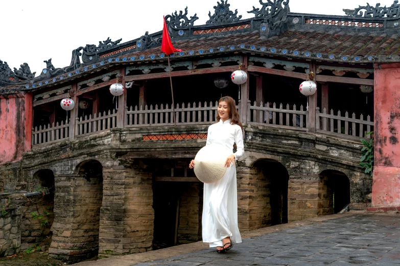 an asian pregnant woman walking down a stone bridge