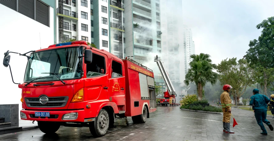 people standing on a street while a fire truck is parked on a road