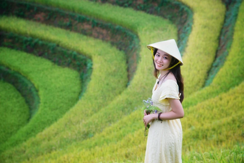 an asian woman in a white hat standing by the grass