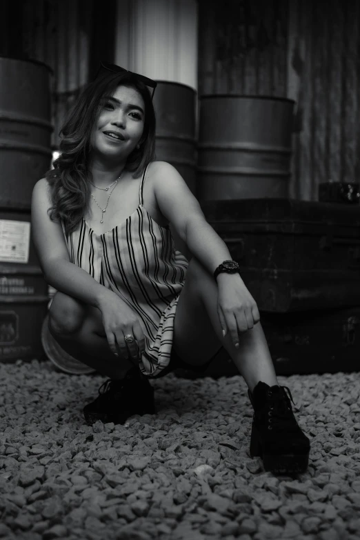 black and white image of a woman sitting on rocks with her legs crossed