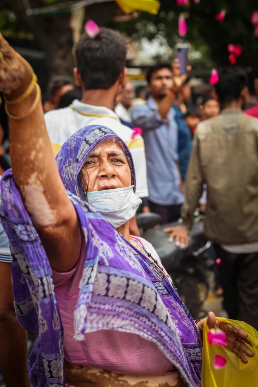 a woman wearing a mask and holding up a hand