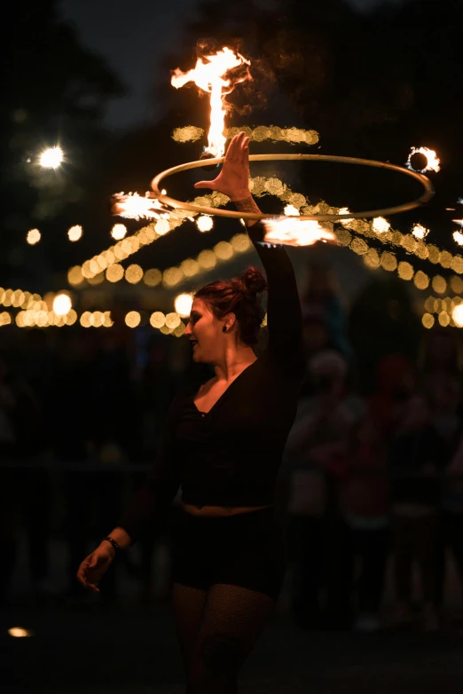 a woman in a black dress holding a fire stick