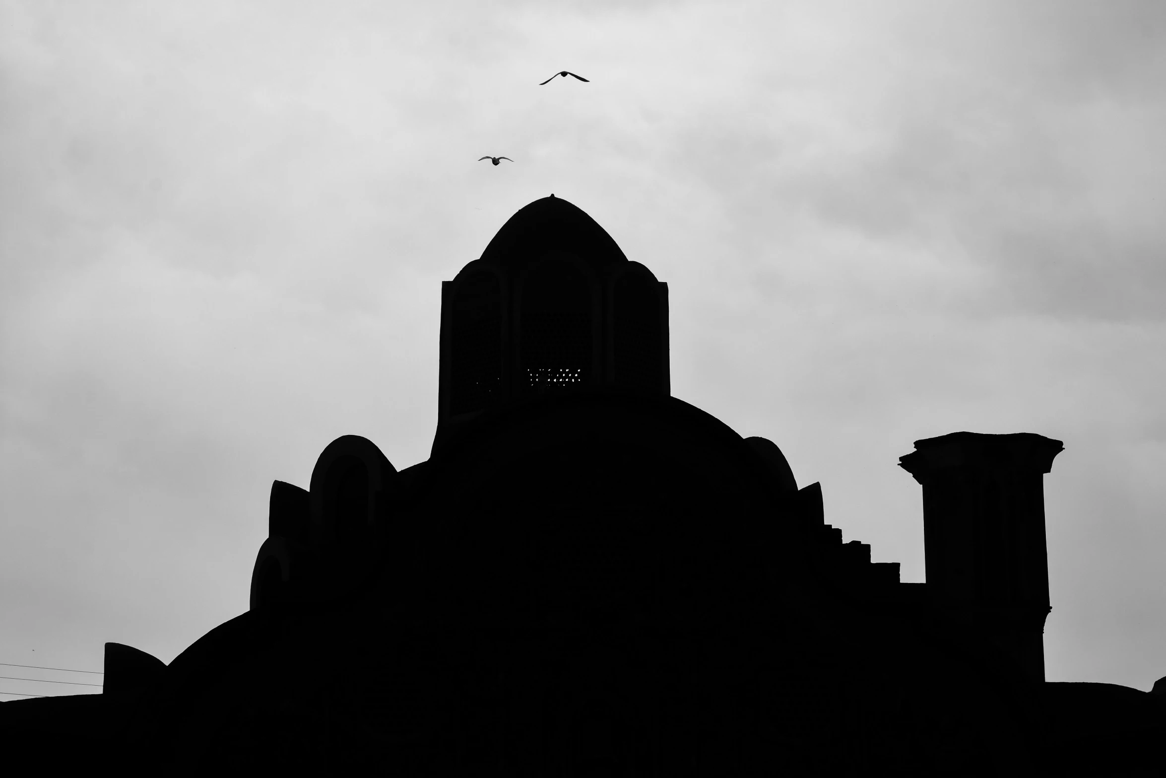 a building under a cloudy sky has two birds flying