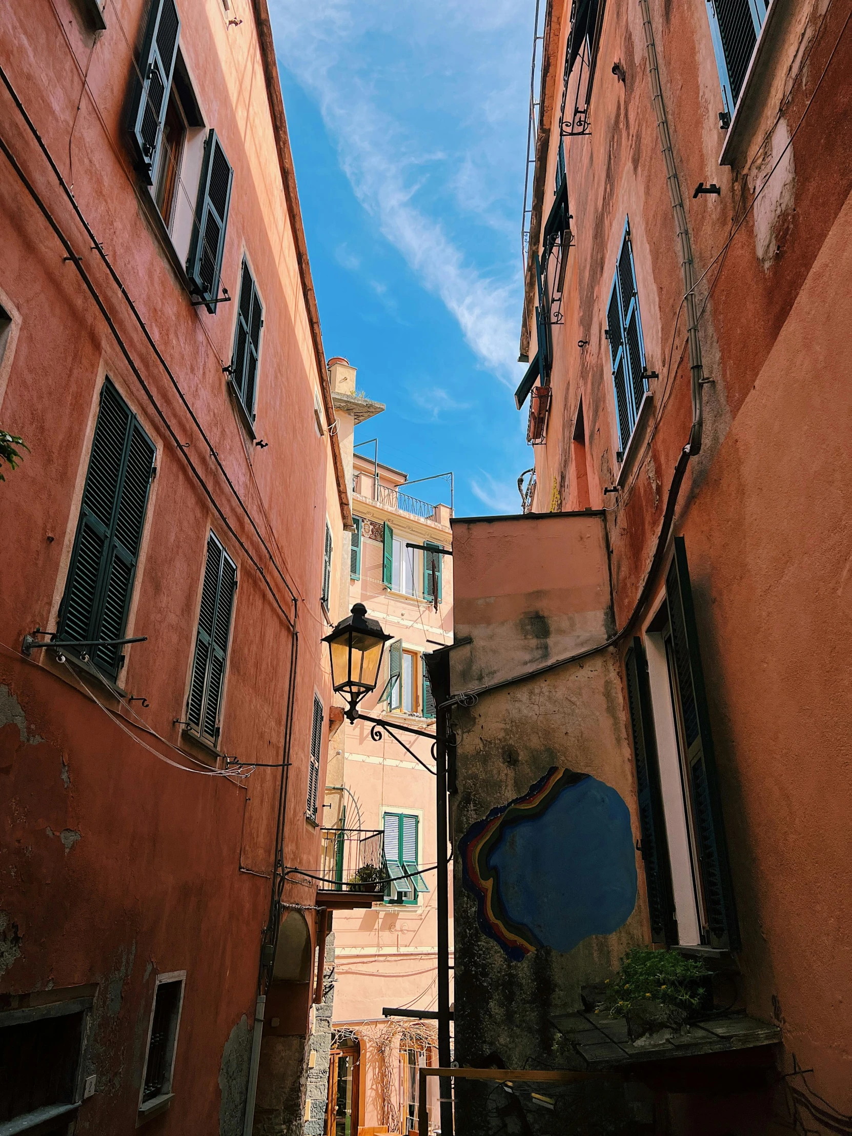 a narrow alleyway with many windows and hanging pots