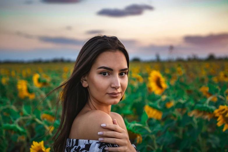 a beautiful young woman standing in a field of sunflowers