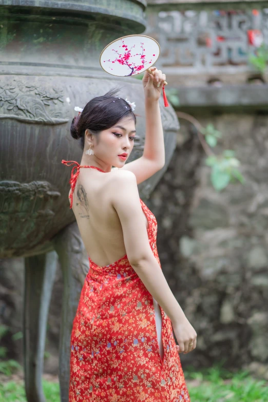 an asian woman wearing a red dress holds a frisbee