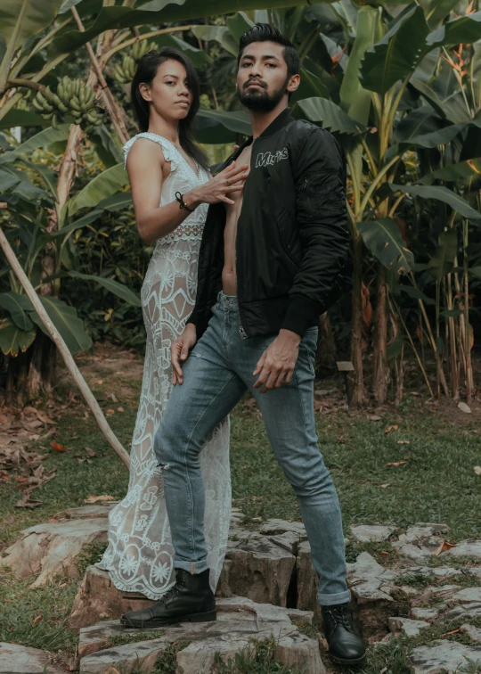 man and woman posing in front of lush green trees