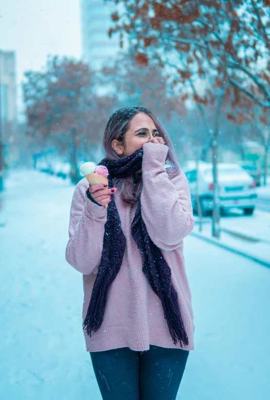 a woman is holding an ice cream cone with a scarf over her neck