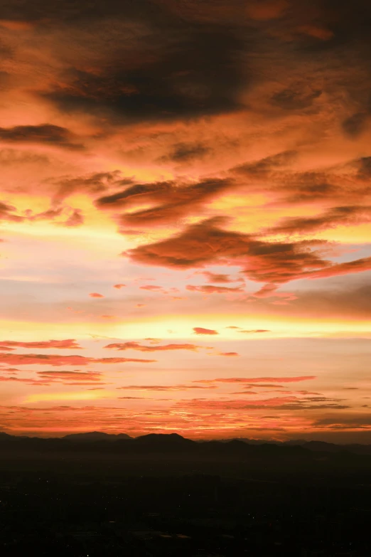 an orange and pink sunset with mountains below