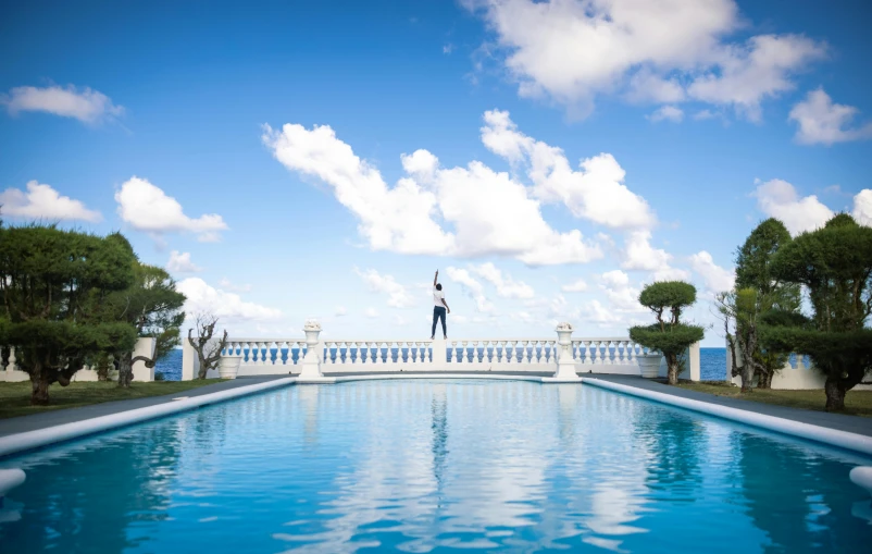 the man is standing on the top balcony above the pool