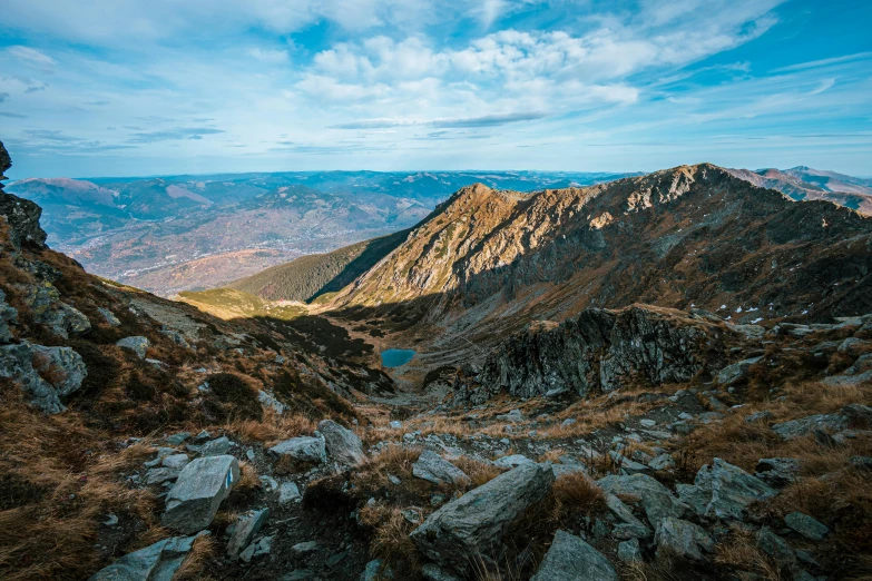 view over a rocky valley and a valley with a lake on the horizon