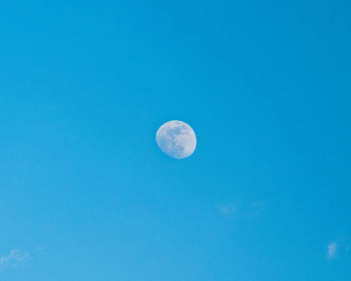 a bright blue sky with the moon in the middle