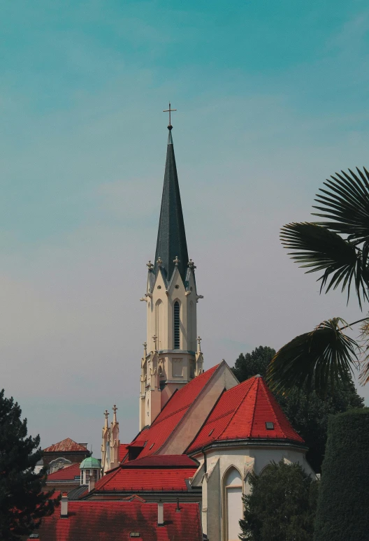 a church with red roofs and steeple next to trees