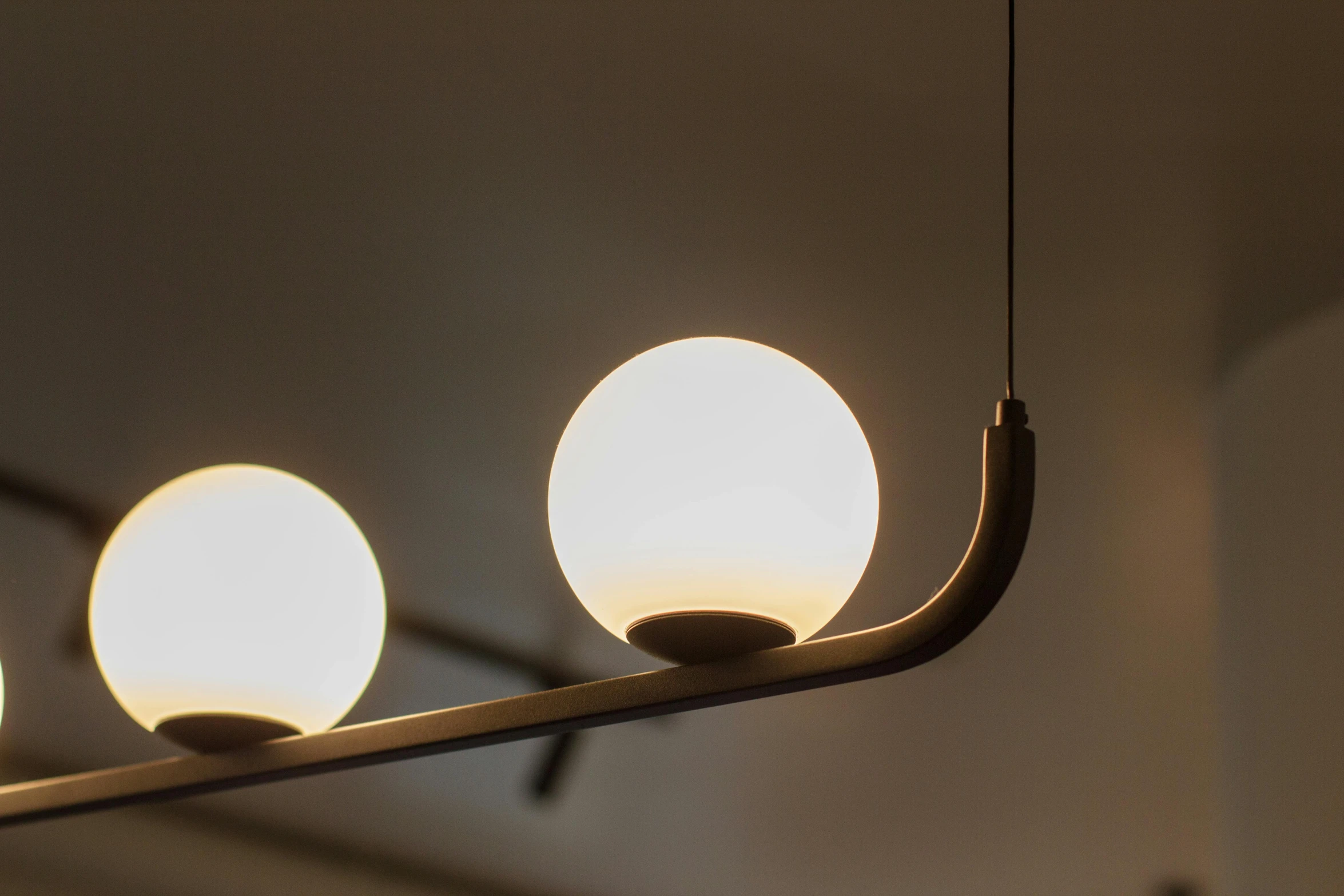three white ball lights hanging in a row on a rod