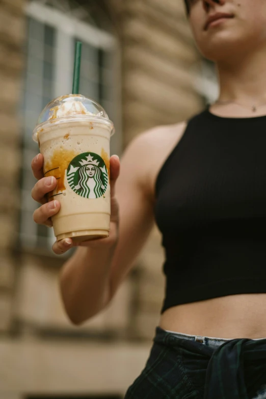 a person holding up a starbucks drink in front of her