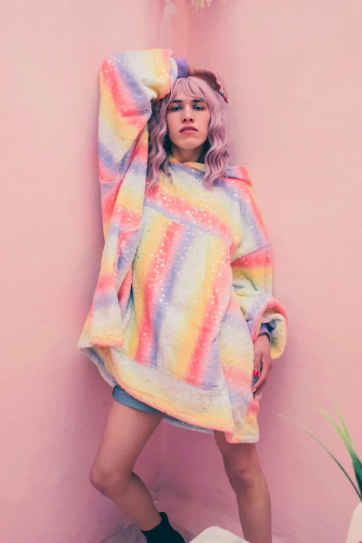 a woman wearing rainbow clothes posing with pink hair