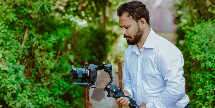 a man holding an electronic camera outside during the day