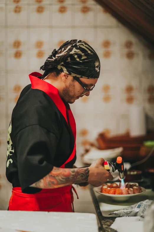 a man in glasses is standing in a kitchen making a small dish