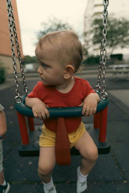 a baby wearing shorts is sitting on a swing
