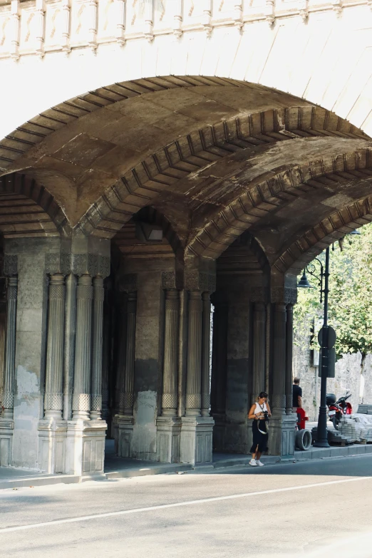 an overpass, people stand under it on the side walk