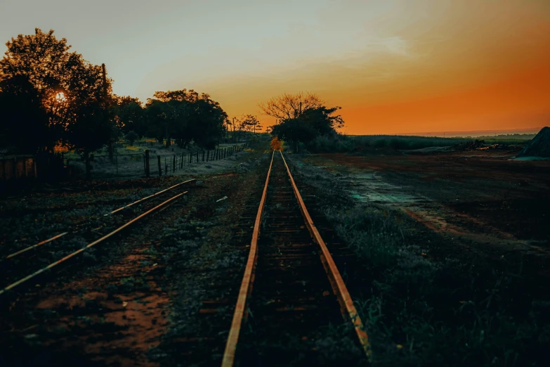 train tracks with sunset sky in background