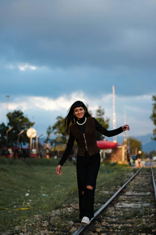 the woman is walking on railroad tracks near a parking lot