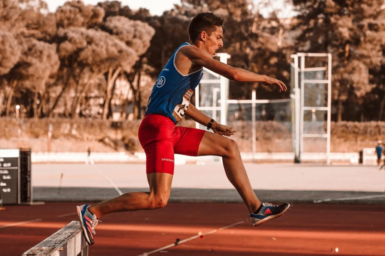 a man in a blue shirt and red shorts jumping into the air on top of a tennis court