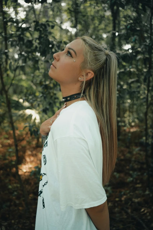 a woman with a pony tail stands in a forest