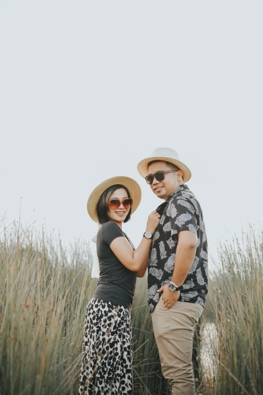 the man and woman are posing in front of tall grass