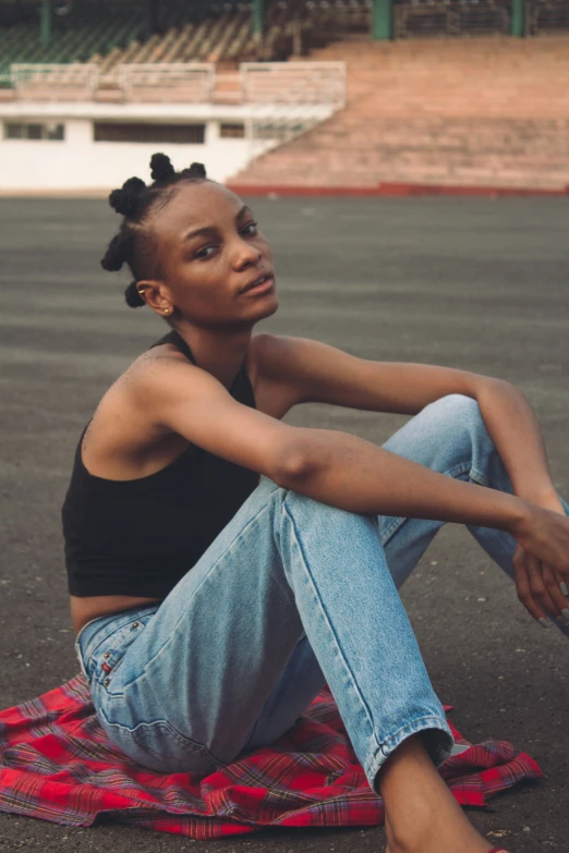 a black woman sits on a blanket near a stadium