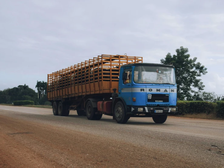 a blue truck is on the road with a wooden back