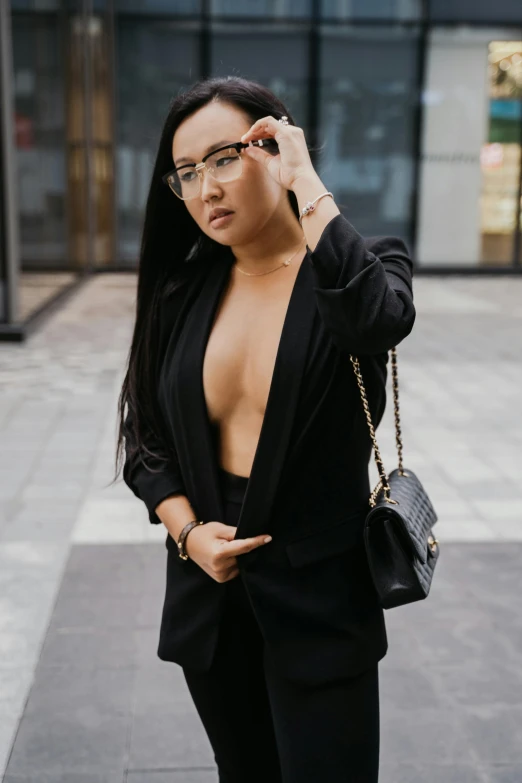 a woman wearing glasses and holding a purse in one hand