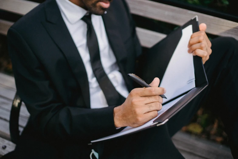 a man in a suit signing soing on a folder