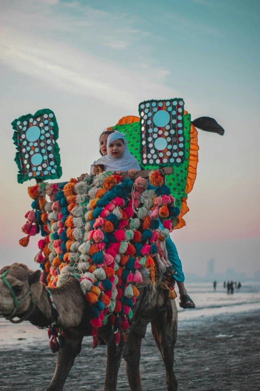 a woman standing on a camel that is covered in items